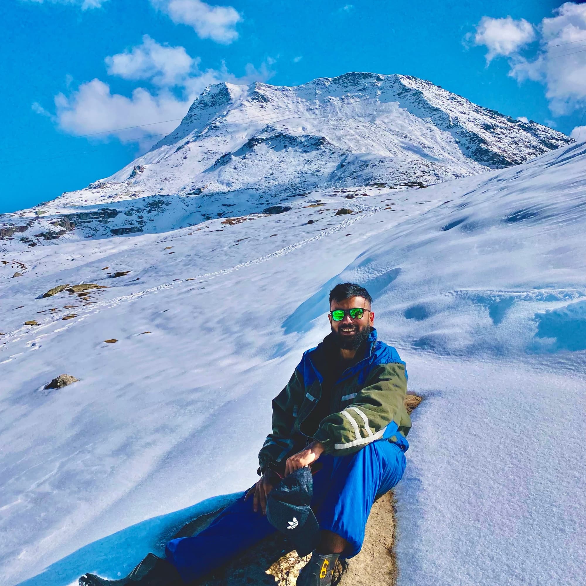 Kunal sitting in the snow below a Himalayan peak