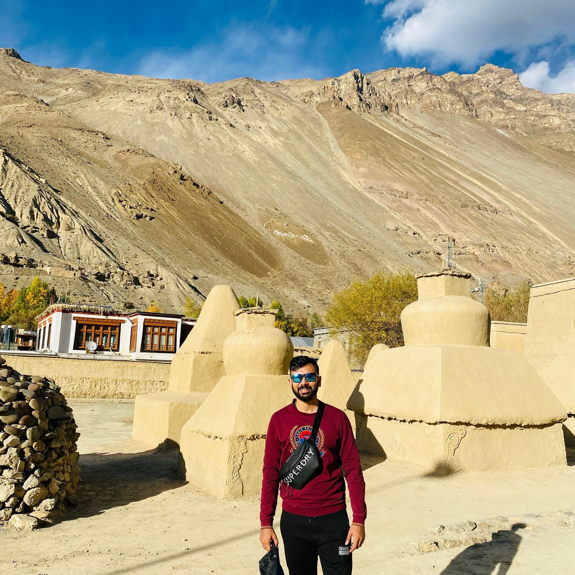 Kunal standing beside stupas in a high Himalayan valley